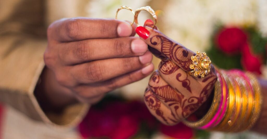 Close-up of hands with henna and jewelry during a traditional Indian wedding ceremony, exchanging rings.