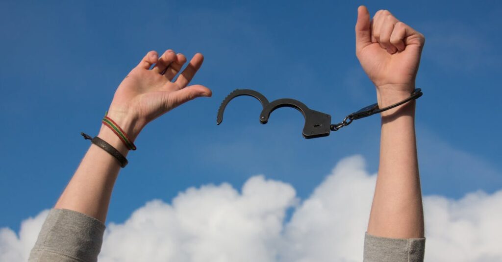 Symbolic image of freedom with open handcuffs against a bright blue sky.