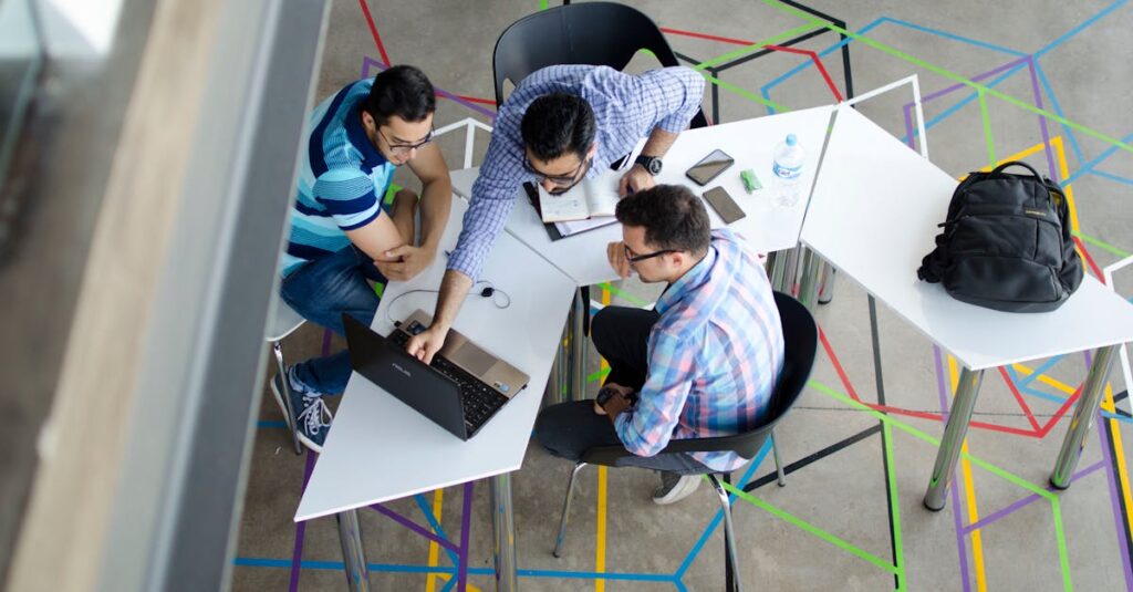 Three men collaborating over a laptop in a modern, geometric-themed office space.