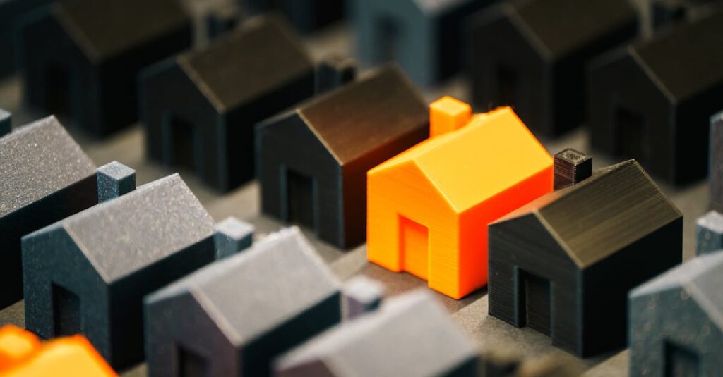 pexels-photo-31370888-31370888 Striking orange model house stands out among black miniature houses, symbolizing real estate choices.