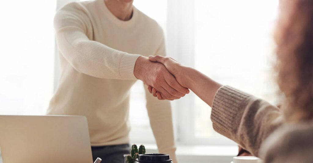 pexels-photo-3184465-3184465 Close-up of professionals shaking hands over coffee in a modern office.