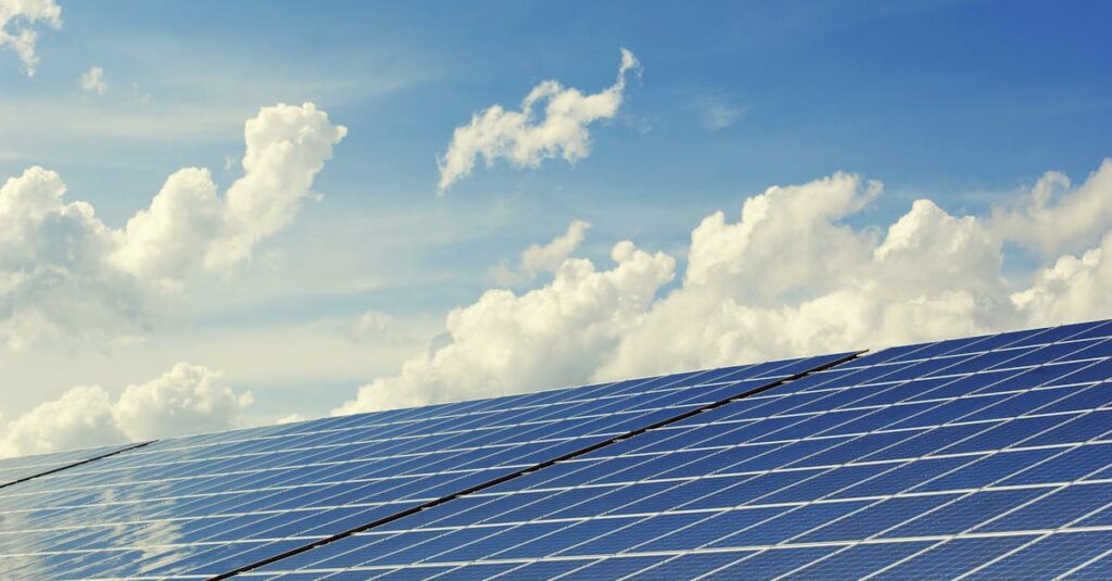 Sleek modern solar panels under a vibrant blue sky with clouds, symbolizing clean energy.