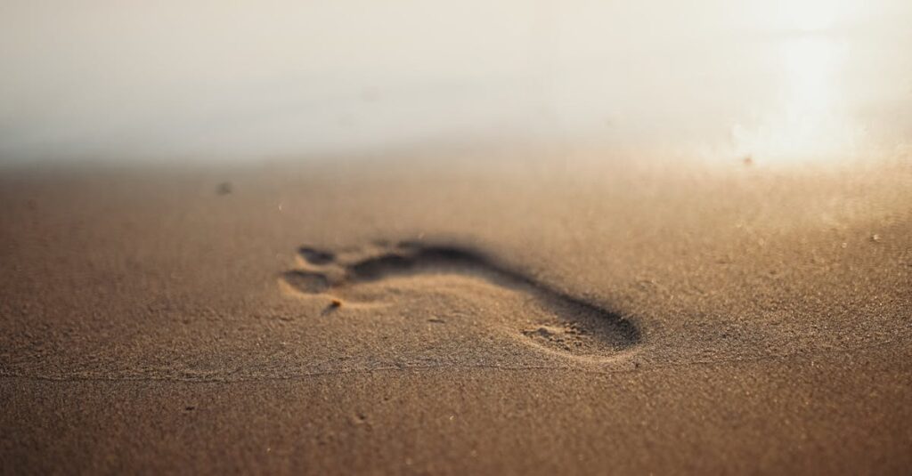 Footprint on sandy beach during sunrise, evoking calm and relaxation.