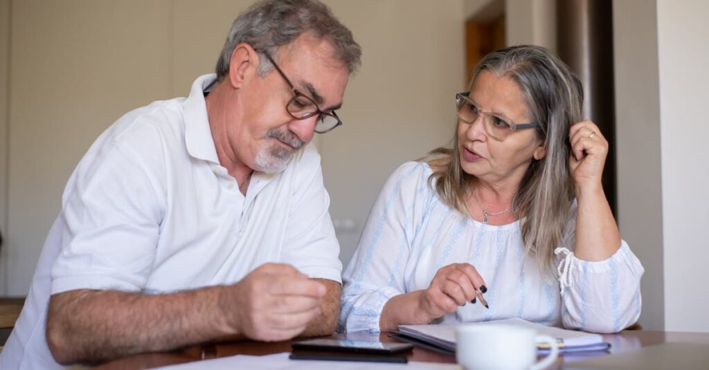 Senior couple reviewing documents and managing finances together at home, showing collaboration and care.